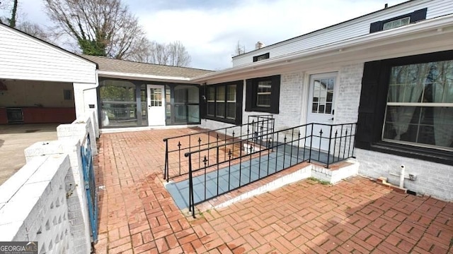 property entrance featuring a patio area and brick siding