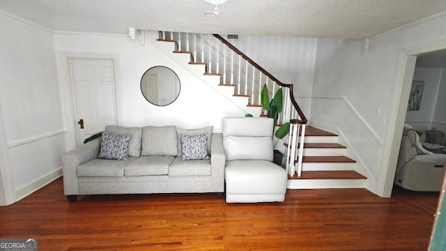 living area with a textured ceiling, stairs, visible vents, and wood finished floors