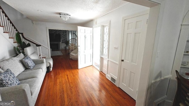 interior space featuring wood finished floors, visible vents, a textured ceiling, and stairs