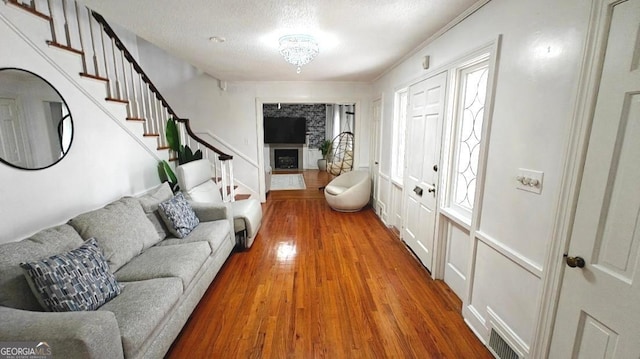 interior space with visible vents, wood finished floors, stairs, a textured ceiling, and a fireplace