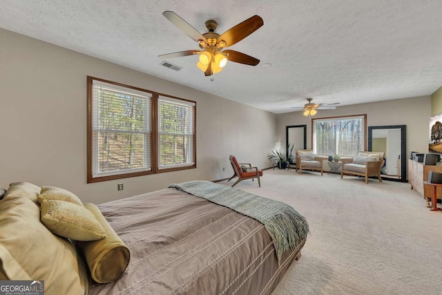 bedroom featuring a textured ceiling, carpet flooring, visible vents, and a ceiling fan