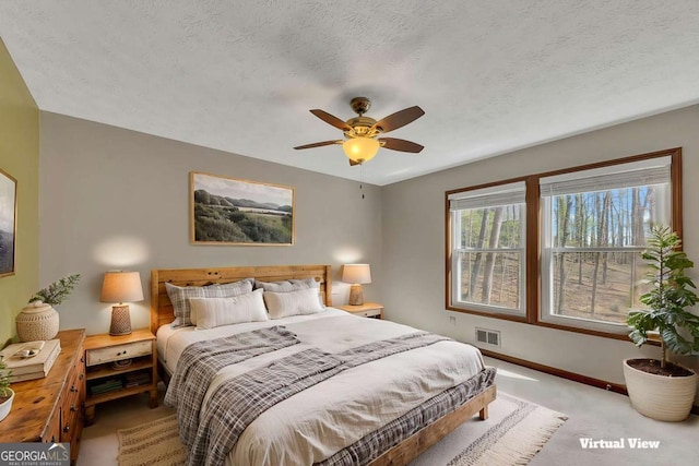 carpeted bedroom featuring a textured ceiling, a ceiling fan, visible vents, and baseboards