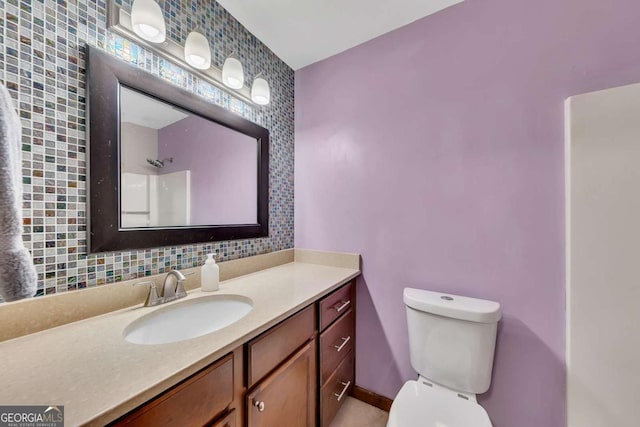 bathroom featuring toilet, baseboards, and vanity