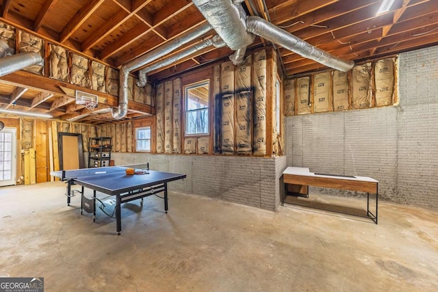 playroom featuring unfinished concrete flooring, plenty of natural light, and brick wall