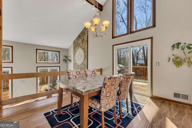 dining space featuring baseboards, wood finished floors, visible vents, and a notable chandelier