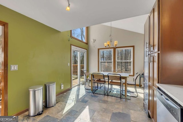 dining space featuring stone tile flooring, baseboards, a notable chandelier, and lofted ceiling