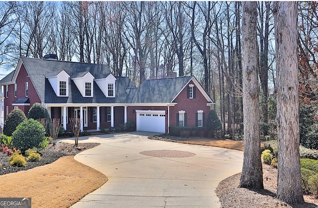 cape cod house featuring brick siding, a shingled roof, concrete driveway, covered porch, and a garage