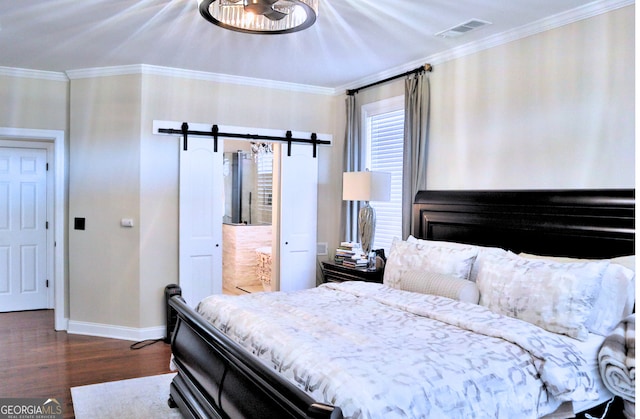 bedroom featuring a barn door, wood finished floors, visible vents, baseboards, and ornamental molding