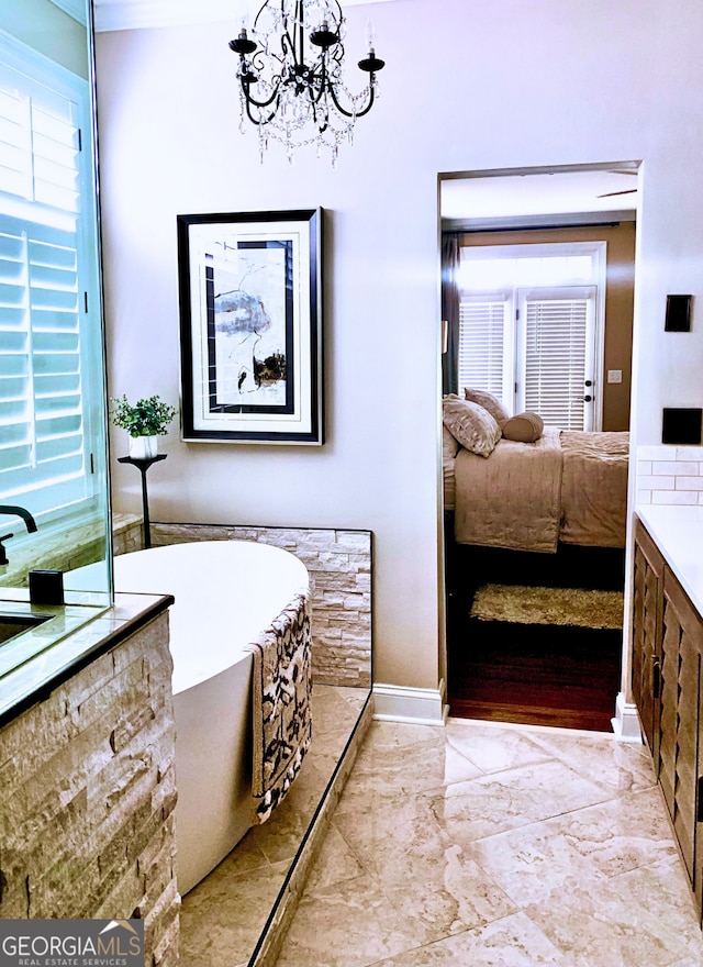 bathroom with baseboards, ensuite bath, marble finish floor, a freestanding bath, and a chandelier