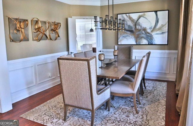 dining room featuring a chandelier, a wainscoted wall, wood finished floors, and a decorative wall