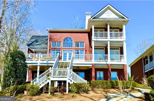 exterior space featuring brick siding, ceiling fan, a chimney, and stairs