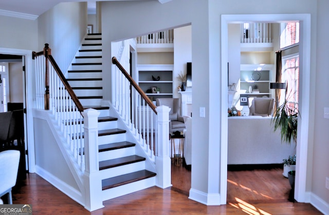 stairway with ornamental molding, a high ceiling, baseboards, and wood finished floors