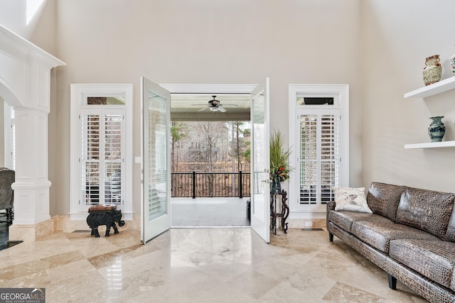 living room featuring a towering ceiling, decorative columns, arched walkways, and ceiling fan