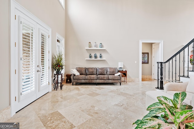 living area with marble finish floor, stairs, a high ceiling, and french doors