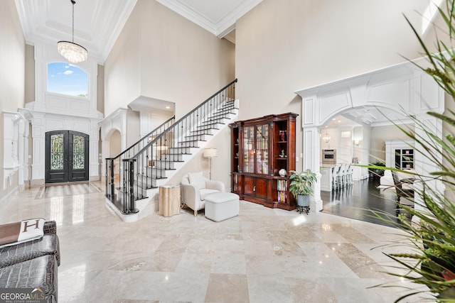 foyer with arched walkways, a towering ceiling, stairs, french doors, and crown molding