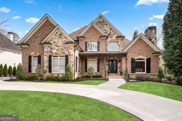 8760 Colonial Pl, Duluth, GA 30097 - view of front of home featuring a porch, brick siding, a front yard, a chimney, and a standing seam roof
