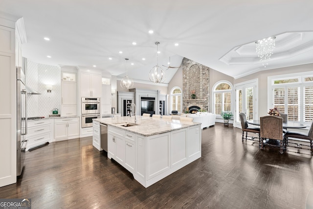 kitchen featuring open floor plan, a fireplace, a sink, and a notable chandelier