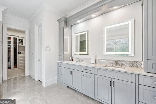 bathroom with marble finish floor, double vanity, a sink, and crown molding