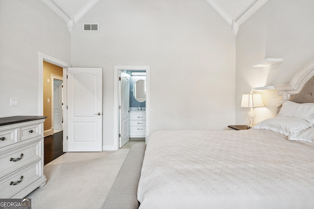 bedroom with connected bathroom, light colored carpet, crown molding, and visible vents