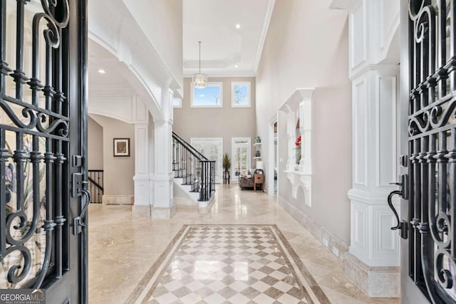 entryway with marble finish floor, crown molding, ornate columns, stairway, and baseboards