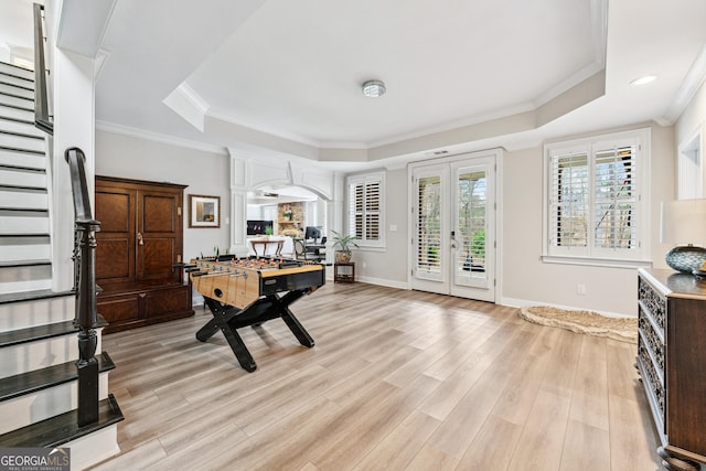 recreation room featuring light wood-style flooring, baseboards, ornamental molding, french doors, and a raised ceiling