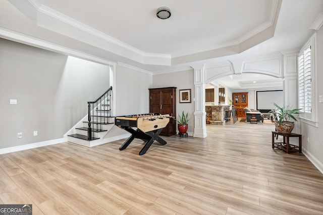 entryway featuring arched walkways, a tray ceiling, decorative columns, light wood-style flooring, and stairs