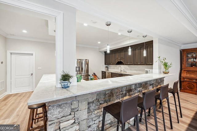 kitchen with light wood-style flooring, a breakfast bar, light stone countertops, crown molding, and stainless steel refrigerator with ice dispenser