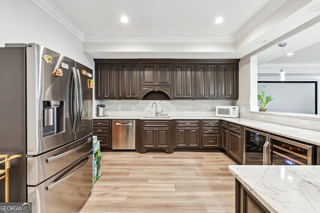 kitchen featuring stainless steel appliances, crown molding, a sink, and dark brown cabinets