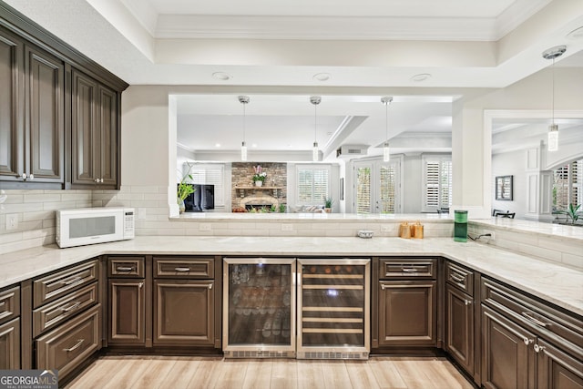 bar featuring tasteful backsplash, white microwave, wine cooler, a tray ceiling, and crown molding