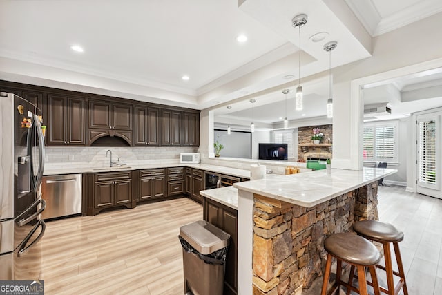 kitchen with crown molding, tasteful backsplash, appliances with stainless steel finishes, a sink, and dark brown cabinetry