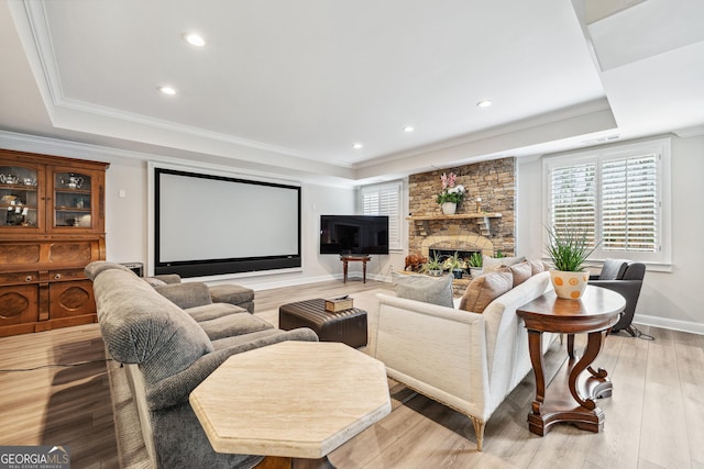 home theater room featuring light wood-style floors, a tray ceiling, and crown molding