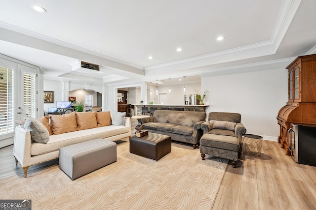 living area featuring arched walkways, a tray ceiling, crown molding, recessed lighting, and light wood-style floors