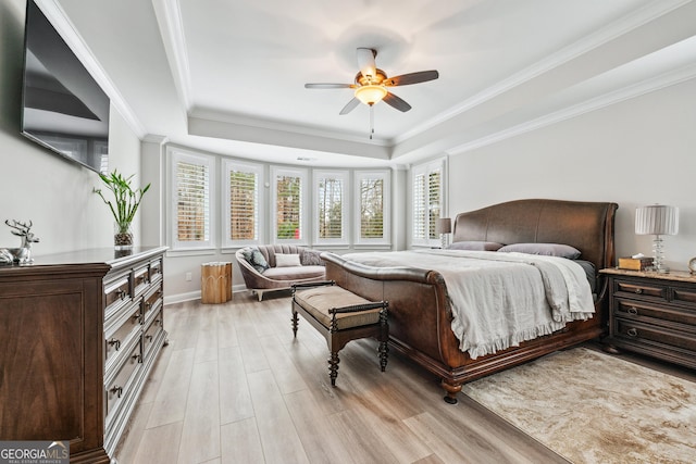 bedroom featuring light wood-style floors, a tray ceiling, and ornamental molding