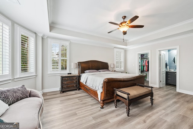 bedroom with a tray ceiling, light wood-style flooring, and baseboards