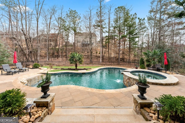 view of pool featuring a pool with connected hot tub, a patio, and fence