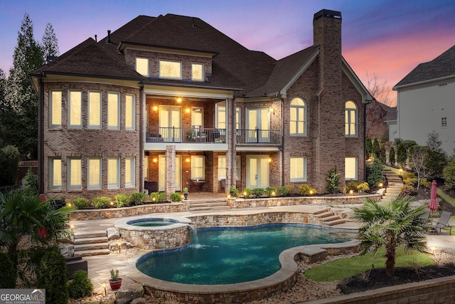 8760 Colonial Pl, Duluth, GA 30097 - back of house at dusk featuring a patio, french doors, a chimney, a balcony, and brick siding