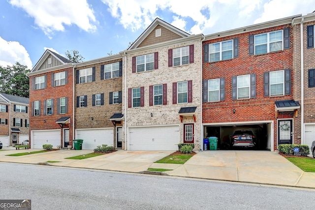 townhome / multi-family property featuring a garage, brick siding, and driveway