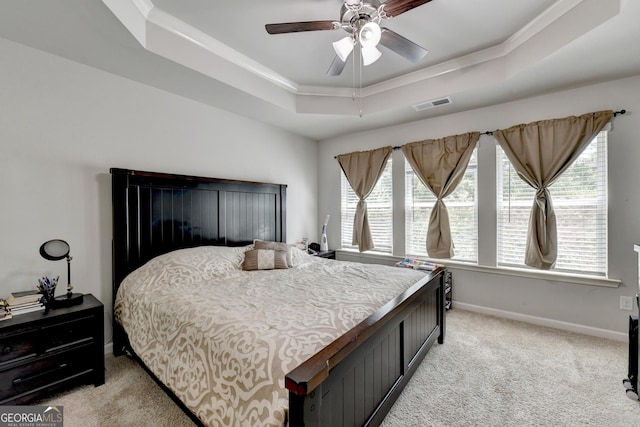 bedroom with visible vents, light carpet, a ceiling fan, a tray ceiling, and baseboards