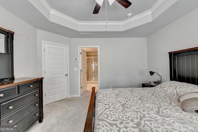 bedroom featuring a ceiling fan, visible vents, a tray ceiling, light carpet, and connected bathroom