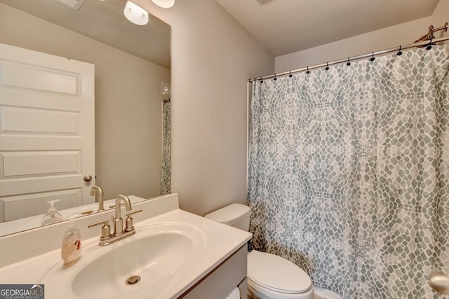 bathroom with curtained shower, toilet, and vanity