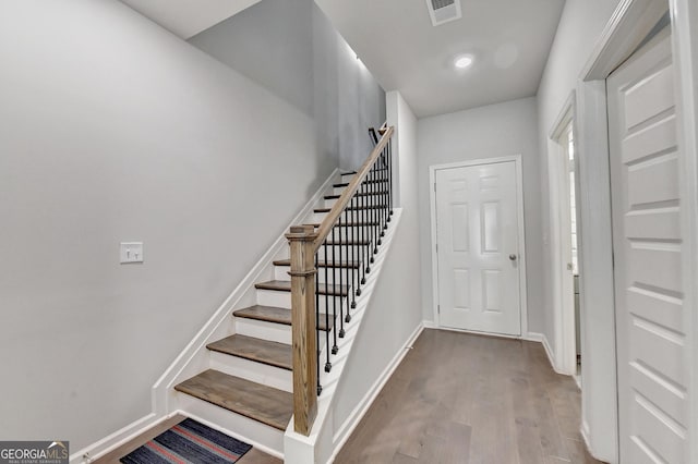 stairs featuring visible vents, baseboards, and wood finished floors