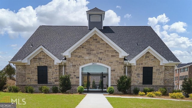 view of front of home with a front yard, a gate, fence, a shingled roof, and brick siding