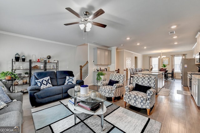 living room with stairway, baseboards, visible vents, crown molding, and light wood-type flooring