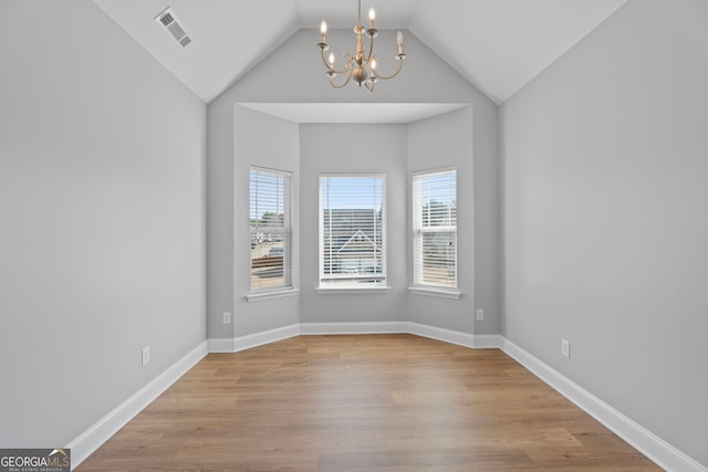 unfurnished room featuring visible vents, vaulted ceiling, wood finished floors, a chandelier, and baseboards