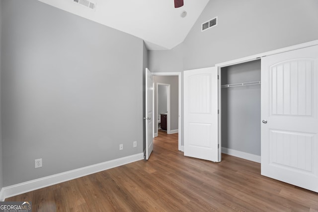 unfurnished bedroom with high vaulted ceiling, wood finished floors, visible vents, and baseboards