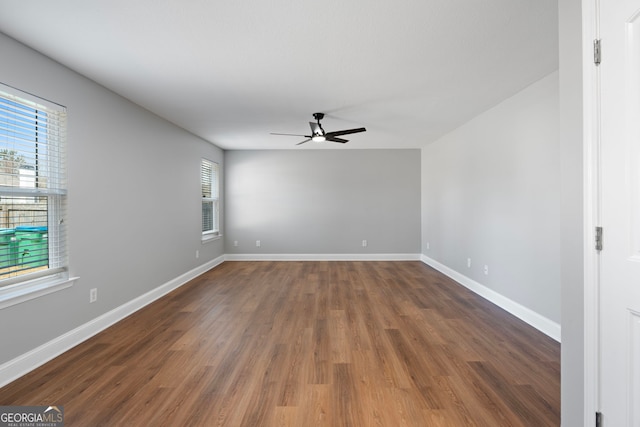 unfurnished room with wood finished floors, a ceiling fan, and baseboards