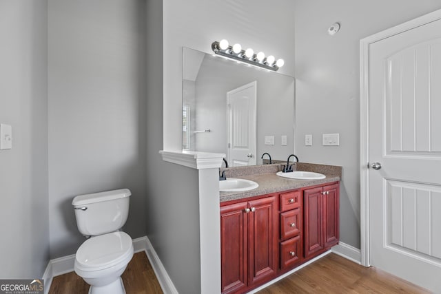 bathroom featuring toilet, baseboards, a sink, and wood finished floors