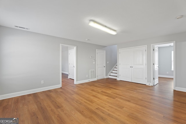 spare room with baseboards, stairs, visible vents, and light wood-style floors