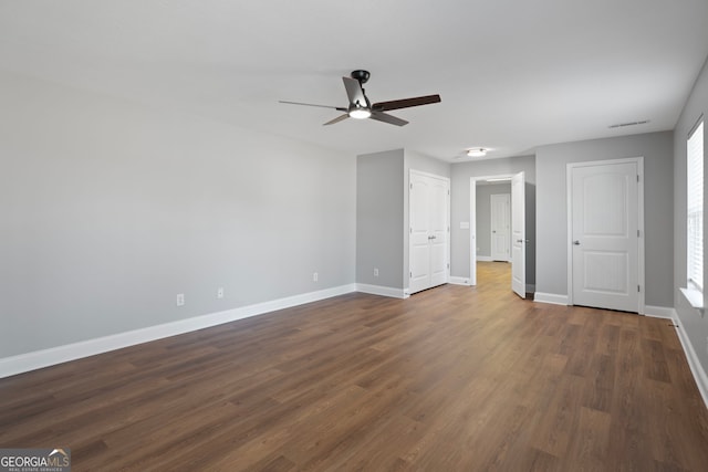 unfurnished bedroom featuring visible vents, dark wood finished floors, a ceiling fan, and baseboards