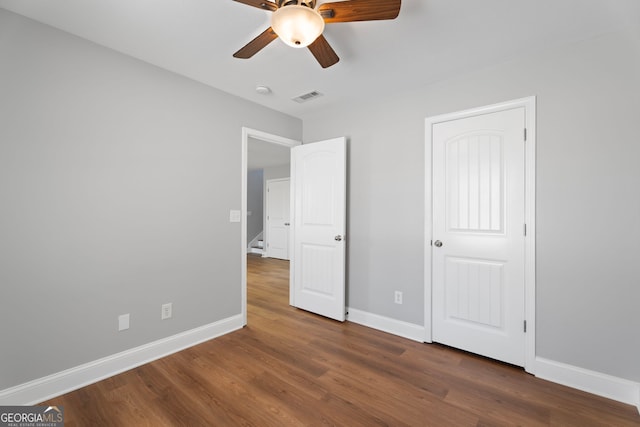 unfurnished bedroom featuring ceiling fan, wood finished floors, visible vents, and baseboards